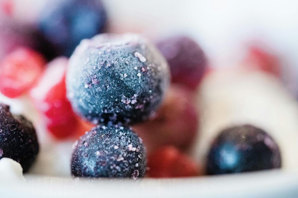 Frozen blueberries and fruits in a close-up shot, showcasing frost and vibrant colors.