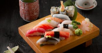 Elegant display of sushi with green tea on a wooden board, capturing authentic Japanese cuisine.