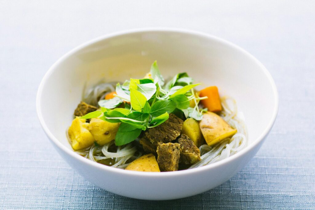 A savory bowl of Vietnamese noodle soup garnished with fresh herbs and vegetables.