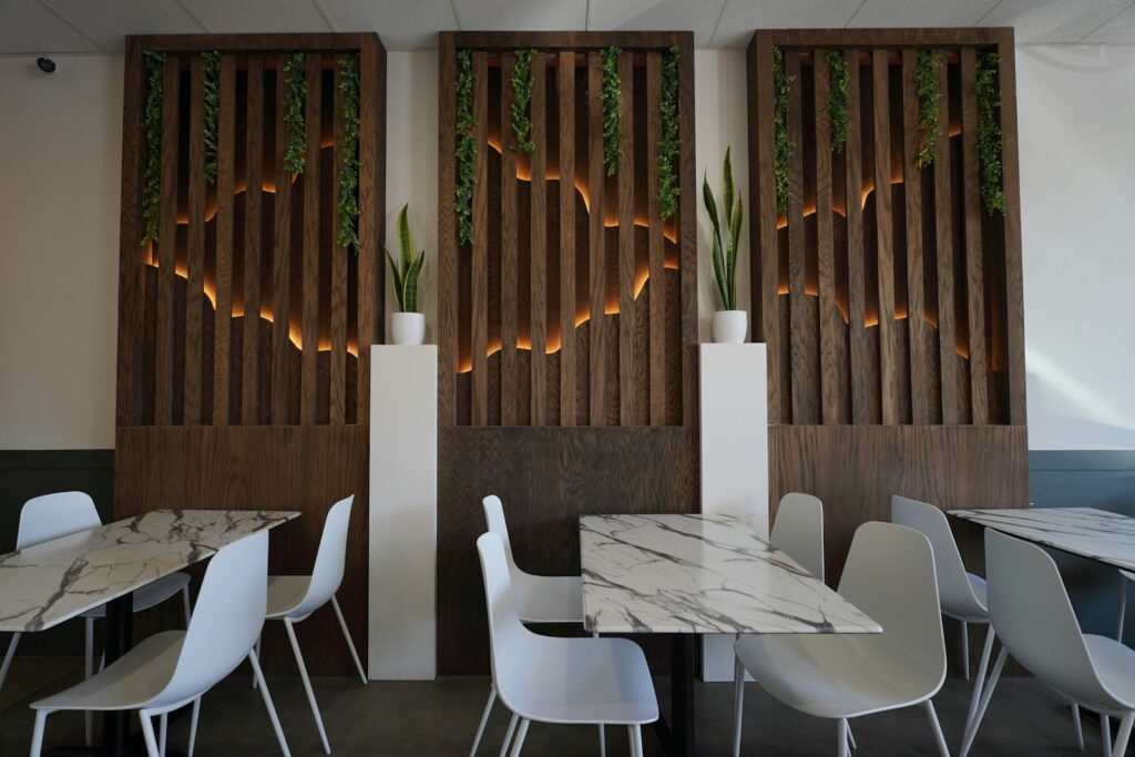 A restaurant with tables and white chairs and wooden screens