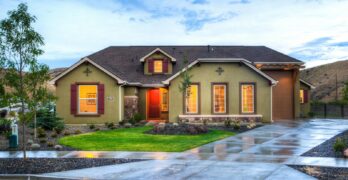 Beautifully illuminated modern home exterior with a lush lawn and wet driveway in Boise, Idaho.