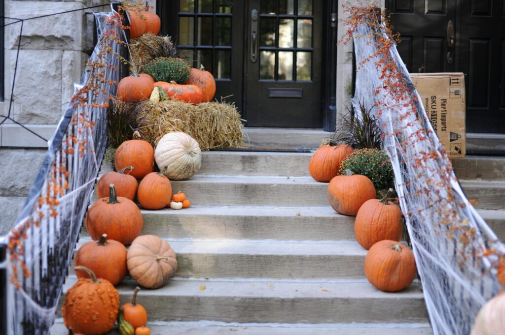 A front porch decorated with pumpkins and spider webs, celebrating Halloween and fall season.
