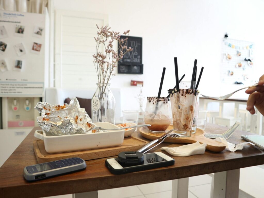 Glass, foil, and utensils clutter a table in a bright, modern setting.