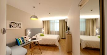 Spacious modern hotel room featuring cozy decor and neutral tones with natural light.