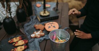 A festive Halloween setup with sweets, cookies, and spooky decorations on a wooden table.
