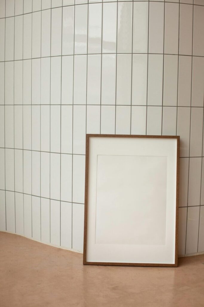 A minimalist interior featuring a blank vertical frame against tiled wall, offering ample copy space.