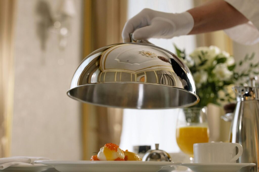 Elegant room service delivering a gourmet breakfast with poached eggs and juice in a luxurious hotel setting.