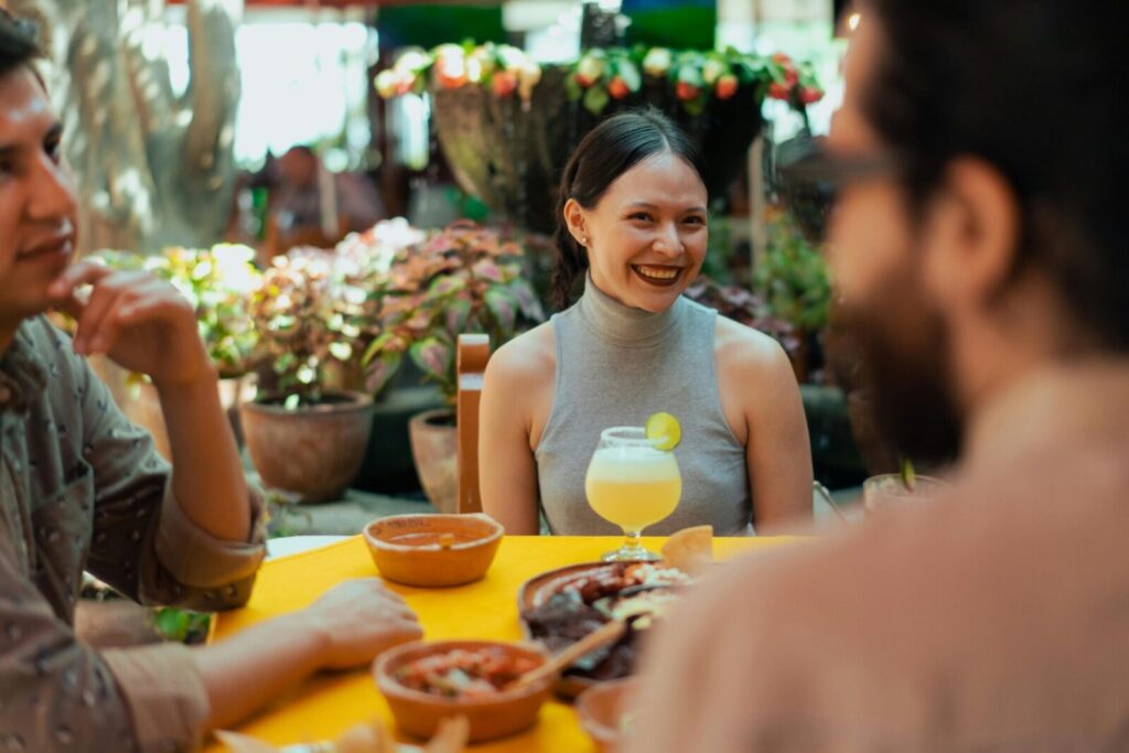 Smiling group of friends at a Mexican restaurant enjoying food and drinks outdoors.