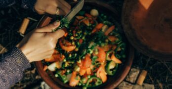 A person cutting up vegetables in a bowl