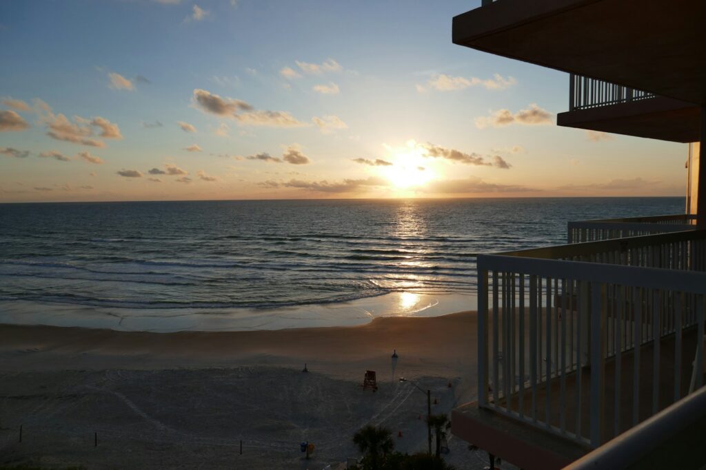 The sun is setting over the ocean from a balcony